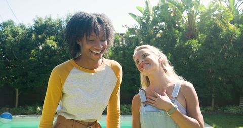 Joyful diverse friends bonding by pool in vibrant back garden