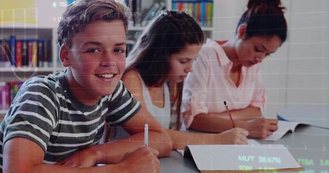 Teen students studying and writing together at library table with futuristic data overlay