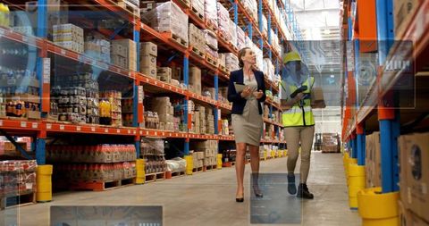 Manager and warehouse worker conducting inventory inspection in busy logistics center