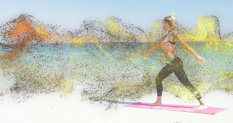 Fit woman practicing yoga lunge on sunny beach amid golden particle waves