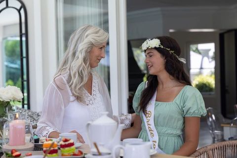 Mother and bride-to-be sharing tea on sunlit patio, intergenerational family bonding