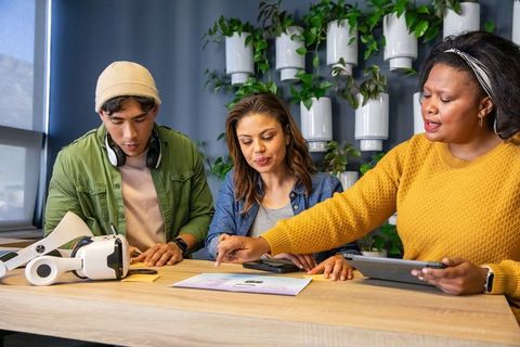 Multicultural team reviewing product mockup with tablet and vr headset in modern office