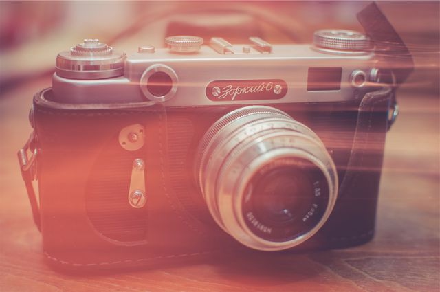 This image features a vintage Soviet camera complete with a leather case, captured in soft, nostalgic lighting with a slight blur effect. It evokes a sense of retro charm and vintage elegance, making it ideal for use in articles, blog posts, or creative projects about film photography, collector's items, or historical photography equipment. Perfect for highlighting nostalgia, representing old-school technology, or enhancing content about Soviet-era collectibles.