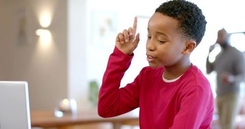 African american boy raising hand during virtual learning at home