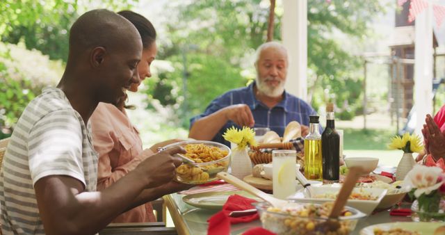 Happy Diverse Husband Serving Food to Family in Sunny Garden during Summer Meal - Download Free Stock Images Pikwizard.com