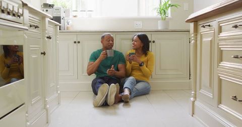 Happy Couple Relaxing on Kitchen Floor with Coffee