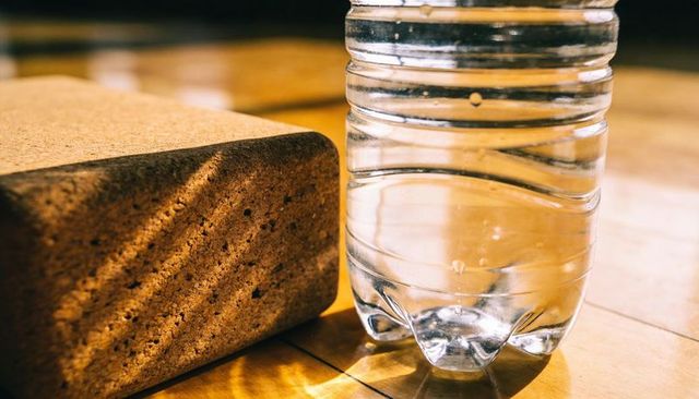 Sunlight casting warm reflections on pet water bottle and cork block on polished hardwood
