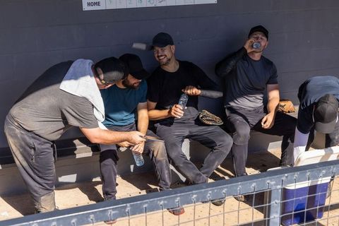 Sunlit baseball team resting in dugout, drinking water and strategizing between innings
