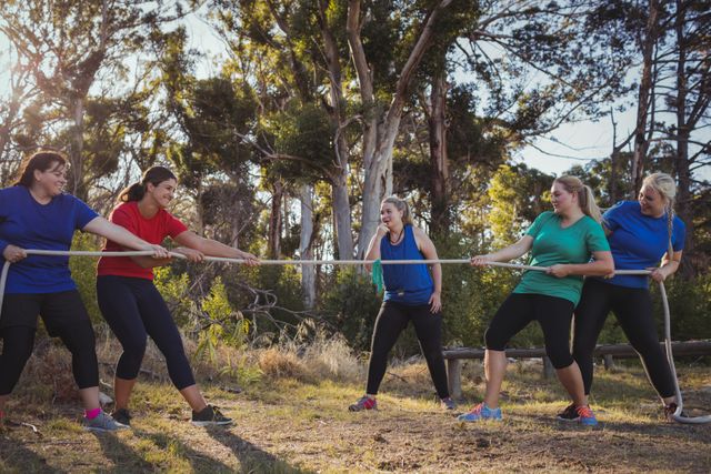 Group of women playing tug of war during obstacle course training in the boot camp
