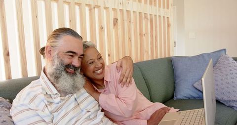 Happy Senior Couple Relaxing with Laptop on Cozy Sofa