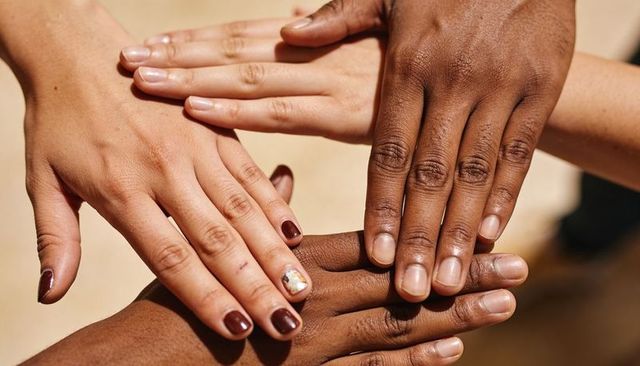 Diverse hands stacking in sunlit unity showing teamwork, solidarity and cooperation