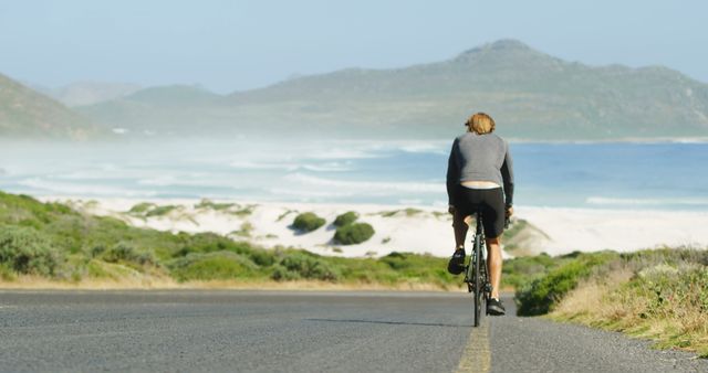 Solo Cyclist Riding Along Coastal Highway with Mountain View - Download Free Stock Images Pikwizard.com