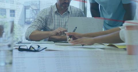 Business Team Collaborating Over Documents and Laptop During Office Meeting