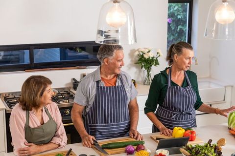 Senior Friends Enjoying Cooking Together in Modern Kitchen Setting