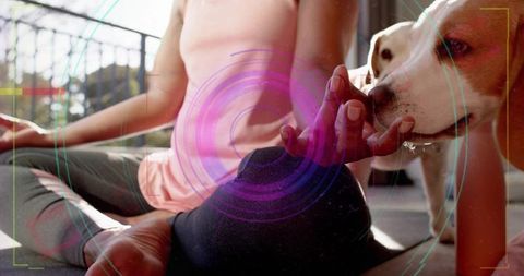 Woman practicing yoga on balcony petting dog during morning meditation
