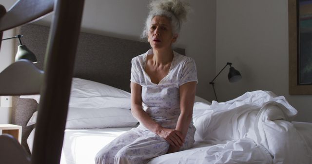 Senior Woman Sitting on Bed with Pensive Expression - Download Free Stock Images Pikwizard.com