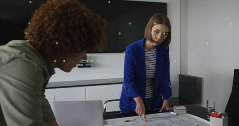 Pointing woman reviewing blueprint with colleague, collaborating on office design