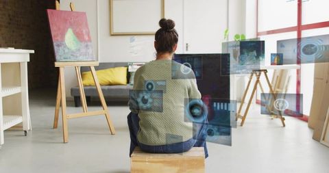 Female artist working in bright studio with holographic panels and augmented reality