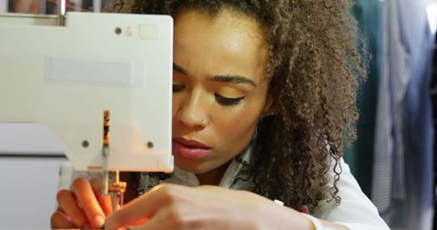 Focused african american fashion designer at sewing machine