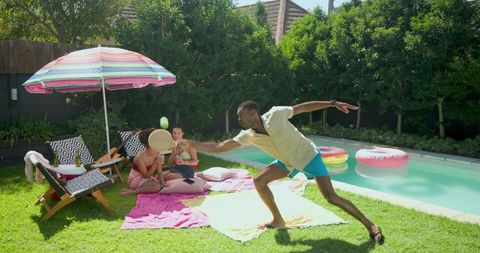 Friends Enjoy Backyard Fun by a Pool with Frisbee Game