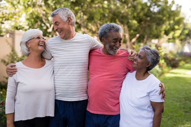 Senior couples are standing together in a park, smiling and enjoying each other's company. This image can be used for promoting active senior lifestyles, retirement communities, friendship, and outdoor activities for the elderly. It highlights the joy of companionship and the importance of social connections in later life.