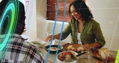 Smiling woman serving roasted chicken at casual home dining table with digital overlay