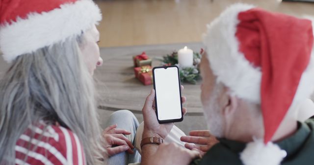 Senior couple wearing Christmas hats video calling on festive holiday afternoon - Download Free Stock Images Pikwizard.com