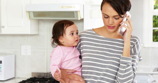 Mother Holding Baby While Talking on Phone in Kitchen - Download Free Stock Images Pikwizard.com