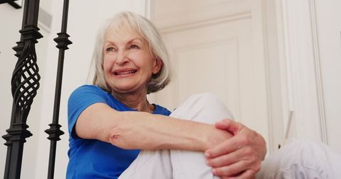 Senior woman smiling on staircase at home in tranquil mood