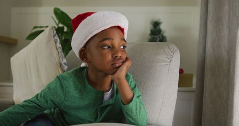 Thoughtful Boy in Santa Hat Relaxing During Christmas Season