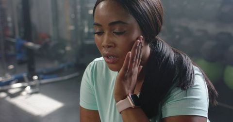 African american woman pressing jaw and catching breath after intense workout in gym studio