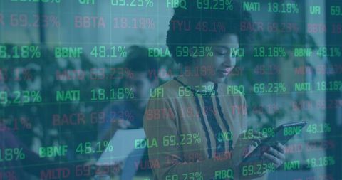 Woman standing using tablet with financial data overlay in open-plan coworking office