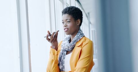 Confident woman recording voice note in modern office