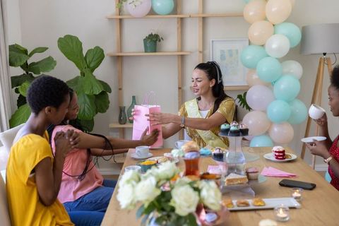 Women Celebrating Home Party Upbeat Atmosphere Hosting Dining Box Gift Giving