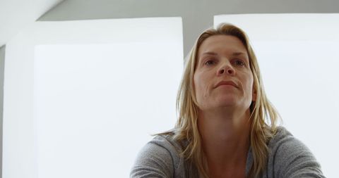Thoughtful woman sitting indoors with natural light