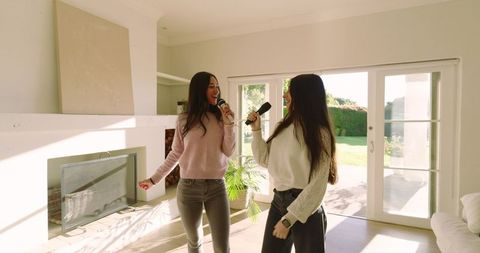 Joyful female friends singing karaoke together