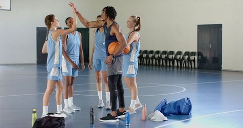 Diverse female basketball team bonding on indoor court