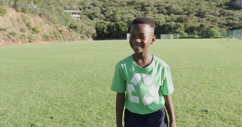 Boy in Green Recycling Shirt Smiling on Soccer Field