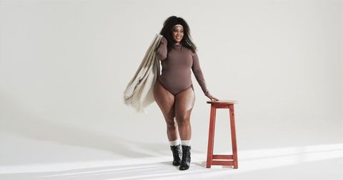 Confident Black Woman Posing in Bodysuit with Red Stool