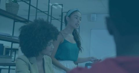 Young professional woman presenting to colleagues in modern office collaboration meeting