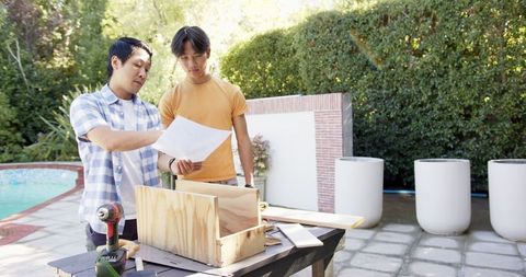 Father and teenage son collaborating on backyard diy project