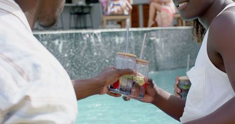 Joyful Couple Enjoying Refreshing Drinks by Poolside