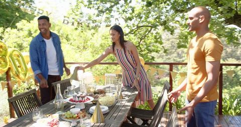 Friends Preparing Outdoor Table for Birthday Celebration on Sunny Day