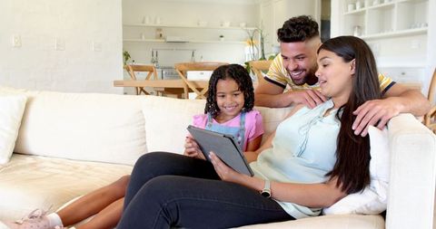 Happy Family Using Tablet on Bright Sofa in Modern Living Room