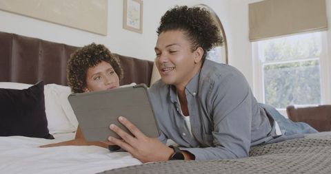 African American Couple Bonding on Bed Sharing Digital Content