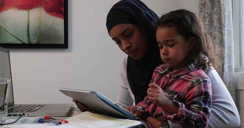 Mother and Daughter Using Tablet at Home Kitchen Table