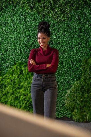Confident african american woman standing with arms crossed smiling against green wall