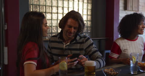 Couple Enjoying Smartphone Entertainment at Bar