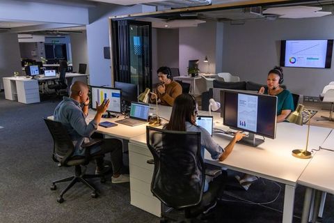 Multicultural team collaborating in open office with headsets and multiple monitors