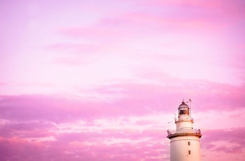 Lighthouse against majestic pink and purple sky at sunset